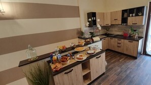A modern kitchen with wooden cabinets, a black countertop, and various food items. - B&B Le Strade del Gavi (Francavilla Bisio)