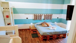 A room with a bed made of wooden pallets, a white chair, and a shelf with decorative items. - B&B Le Strade del Gavi (Francavilla Bisio)