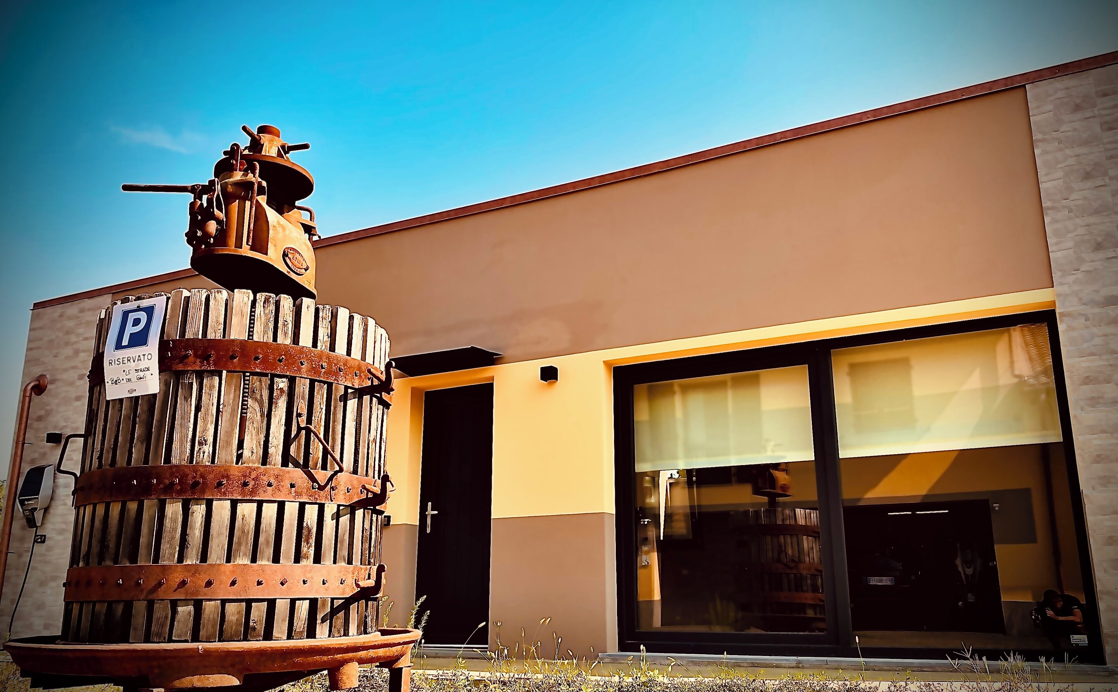 Un edificio con una gran estructura de madera al frente, un cartel de estacionamiento y un escaparate moderno con grandes ventanales.
