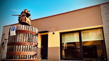 Un edificio con una gran estructura de madera al frente, un cartel de estacionamiento y un escaparate moderno con grandes ventanales.