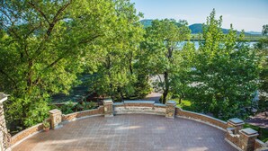 A circular outdoor area with a tiled floor, surrounded by brick walls and trees. - Hotel Livia (Xarrë)