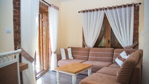 A living room with a brown sofa, a wooden coffee table, and a brick wall. - Hotel Livia (Xarrë)