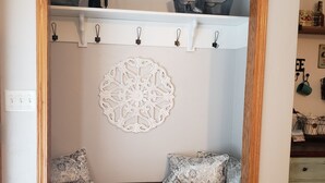 Una habitación acogedora con un banco de madera, un adorno en la pared y un estante con cestas de almacenamiento.