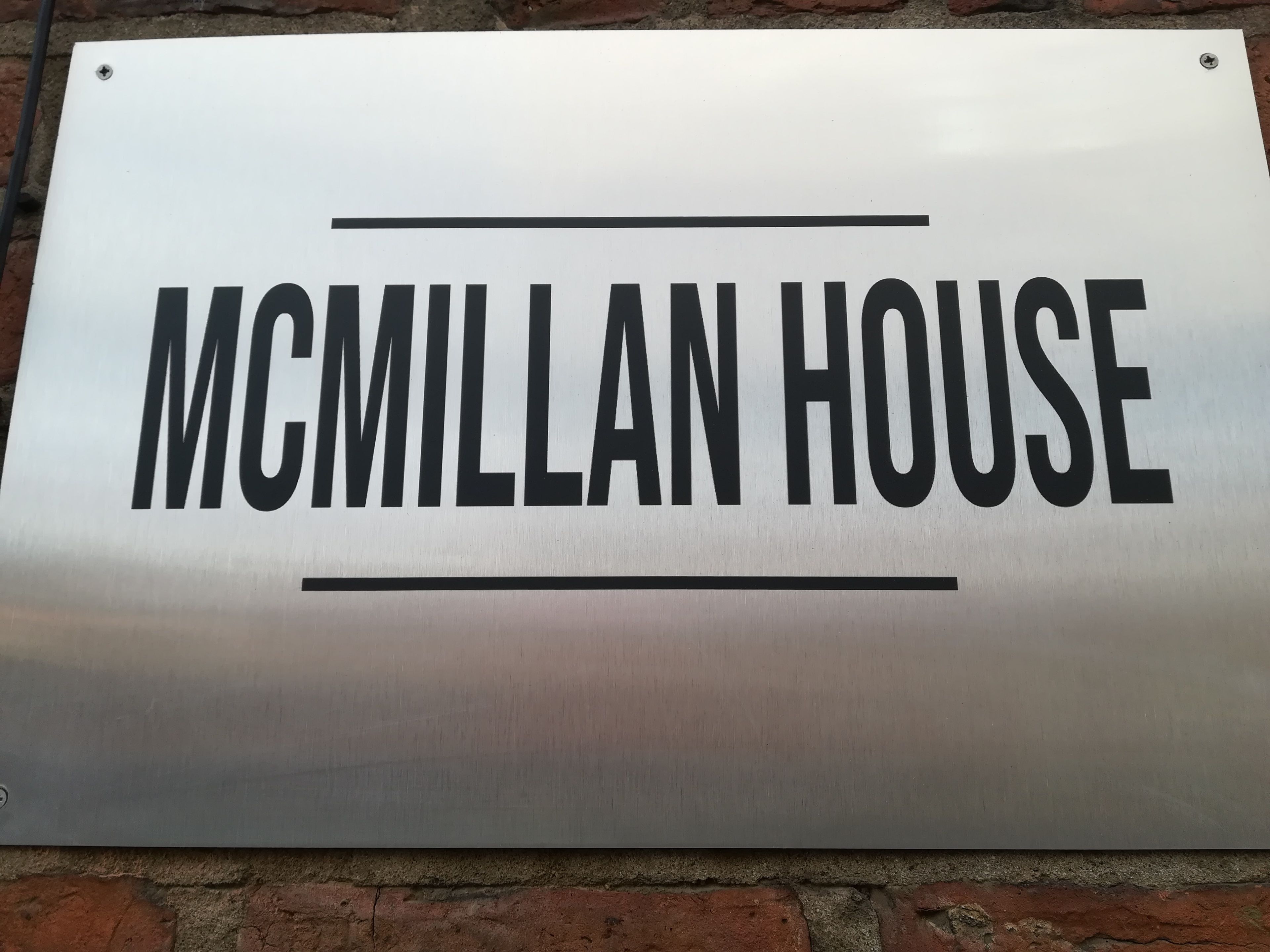 Un cartello con il testo "MCMILLAN HOUSE" su una superficie metallica.