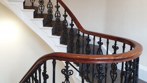A staircase with ornate black iron railings and wooden handrails. - McMillan House Studio Apartments (York)
