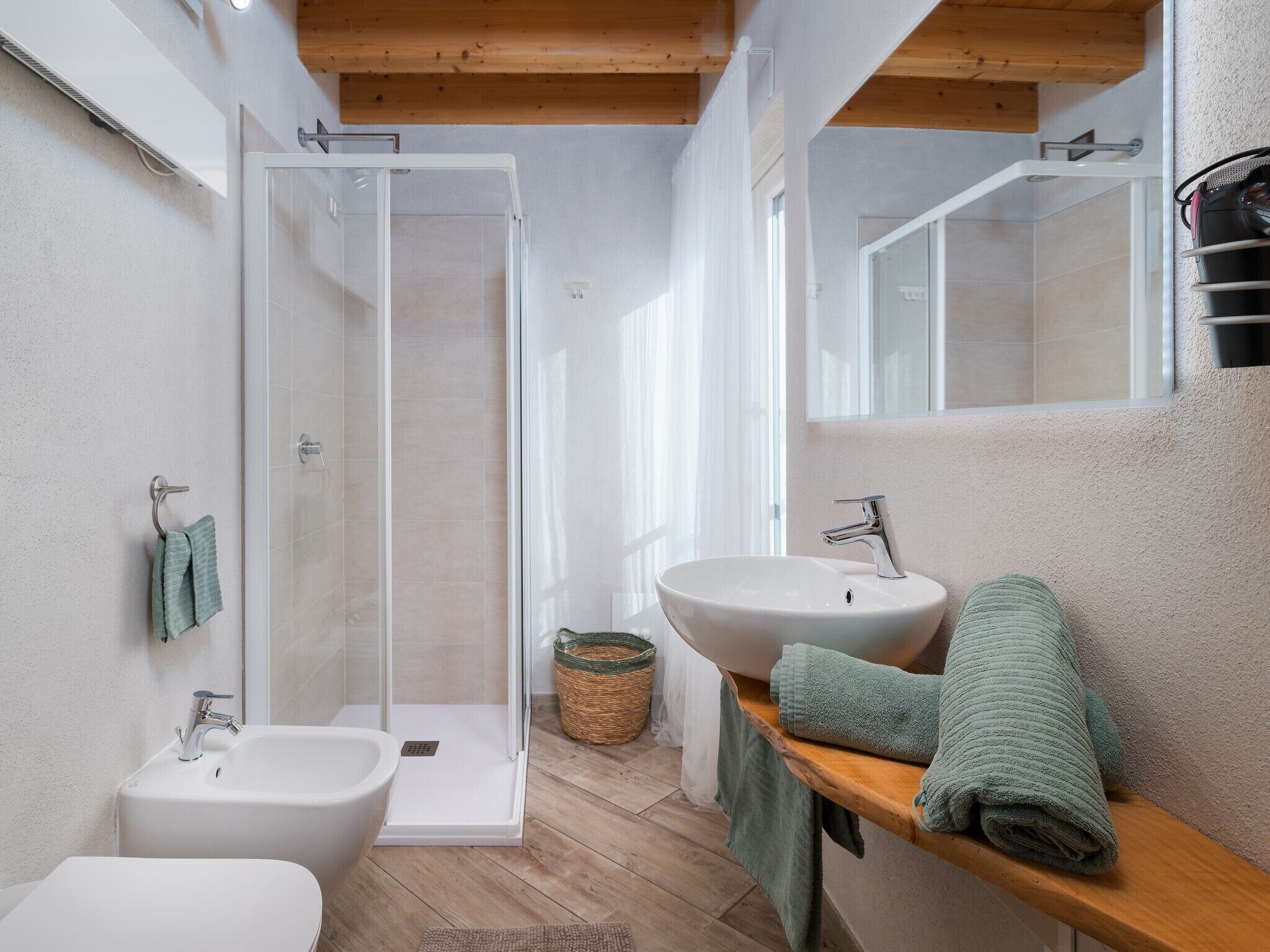 A modern bathroom with a walk-in shower, a bidet, a sink, and a mirror.