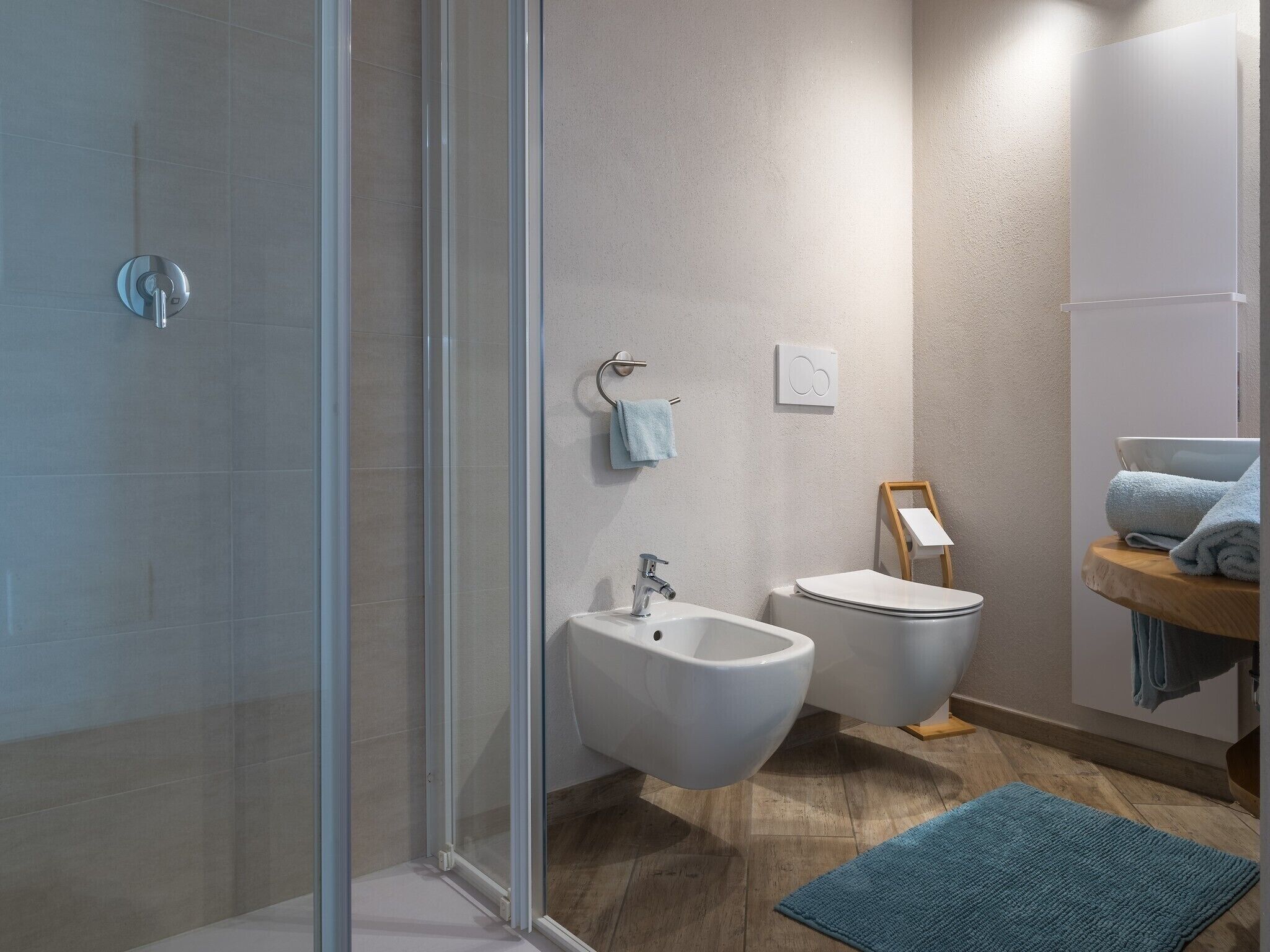 Ein modernes Badezimmer mit Duschkabine aus Glas, einem Bidet, einer Toilette und einem Waschbecken.