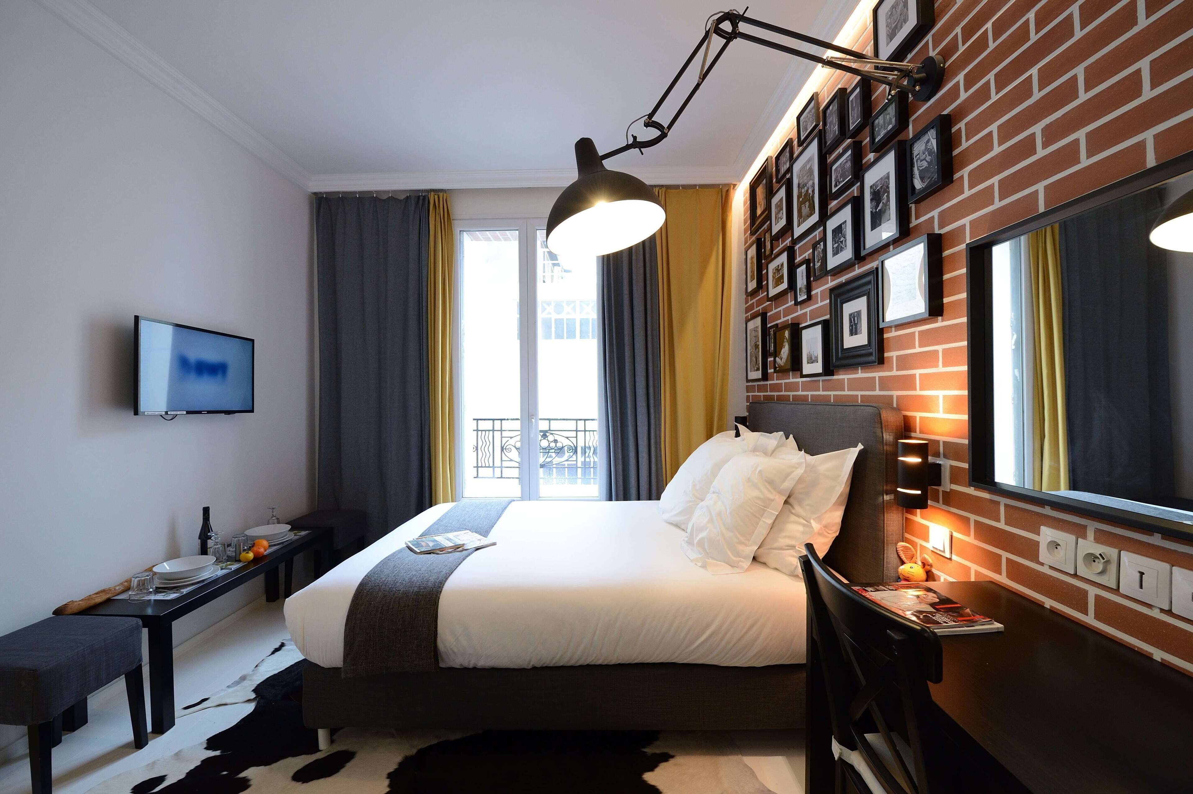 A hotel room with a bed, bedside table, TV, and a window with curtains.