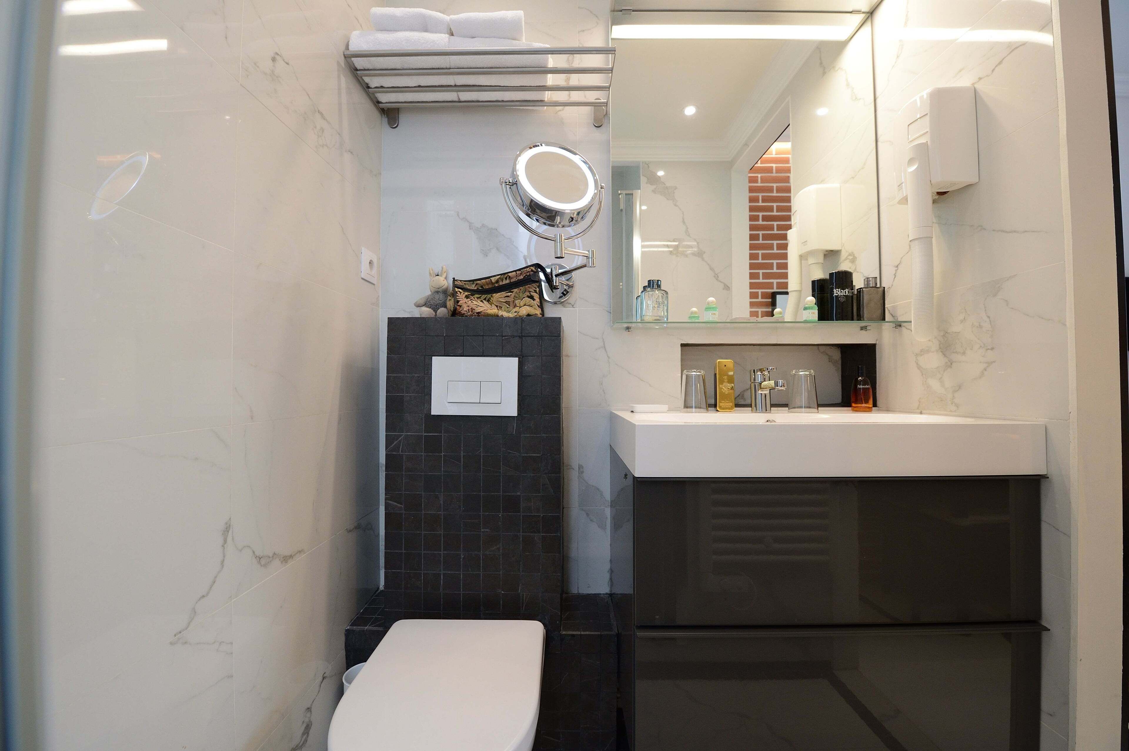 Un baño moderno con inodoro, lavamanos y espejo.