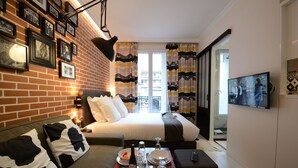 Una habitación de hotel acogedora con pared de ladrillo, una cama con ropa de cama blanca, una mesa de comedor dispuesta con platos y vasos, y un televisor en la pared.