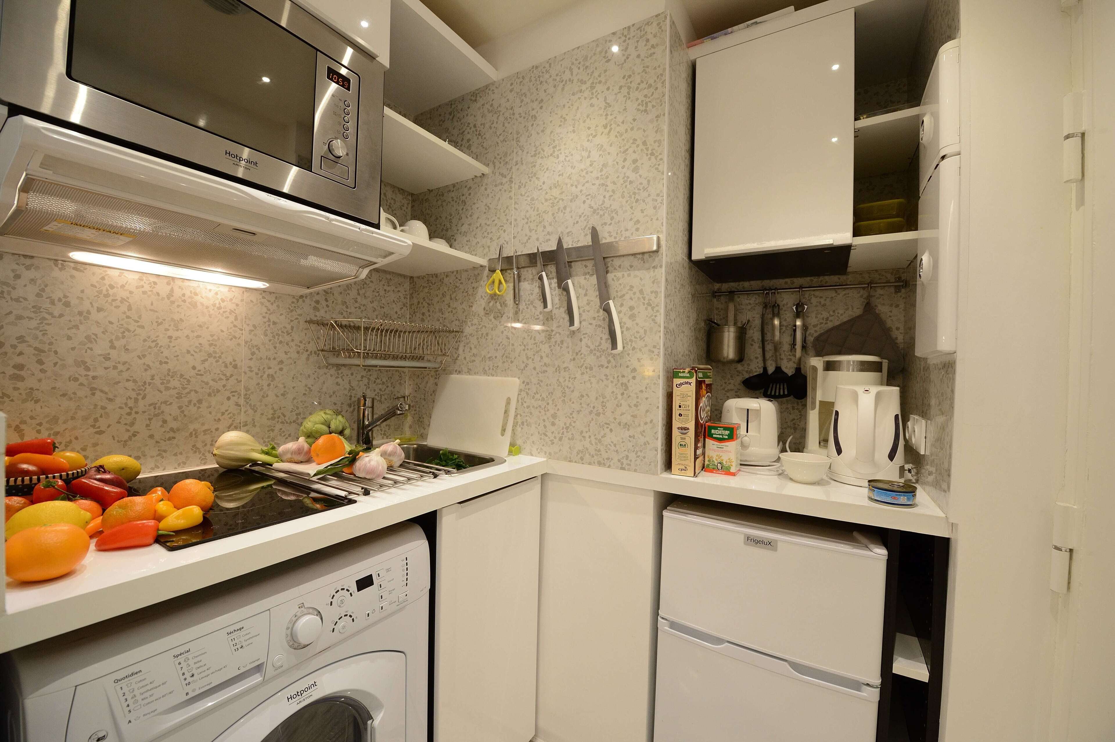Una cuina compacta amb microones integrat, rentaplats i un refrigerador petit.