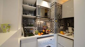 Una cocina compacta con microondas, horno y lavadora integrada.