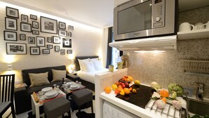 Cocina compacta con microondas, lavamanos y encimera con productos frescos.