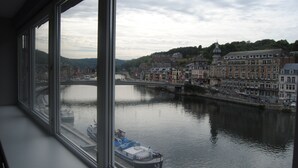 A view of a river with boats, a bridge, and buildings along the riverbank. - L'Inattendu sur la Croisette Dinant Centre (Dinant)