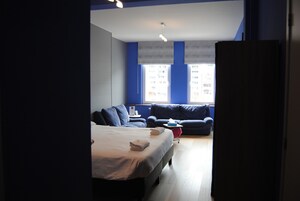 Habitación de hotel con cama, dos sofás, una mesita y ventana con vistas a edificios.
