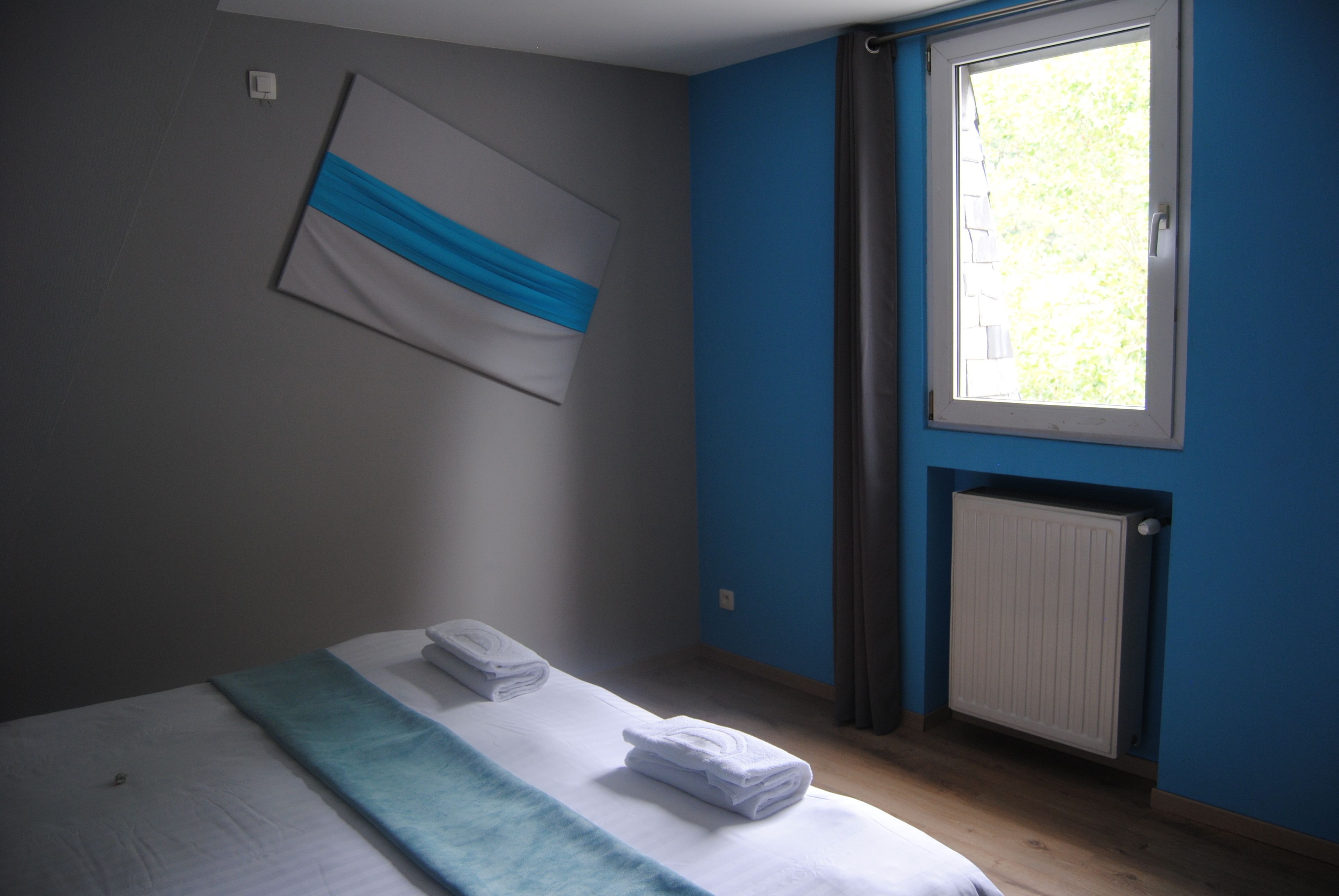 Une chambre à coucher avec un lit, une fenêtre, un radiateur et un porte-serviettes.