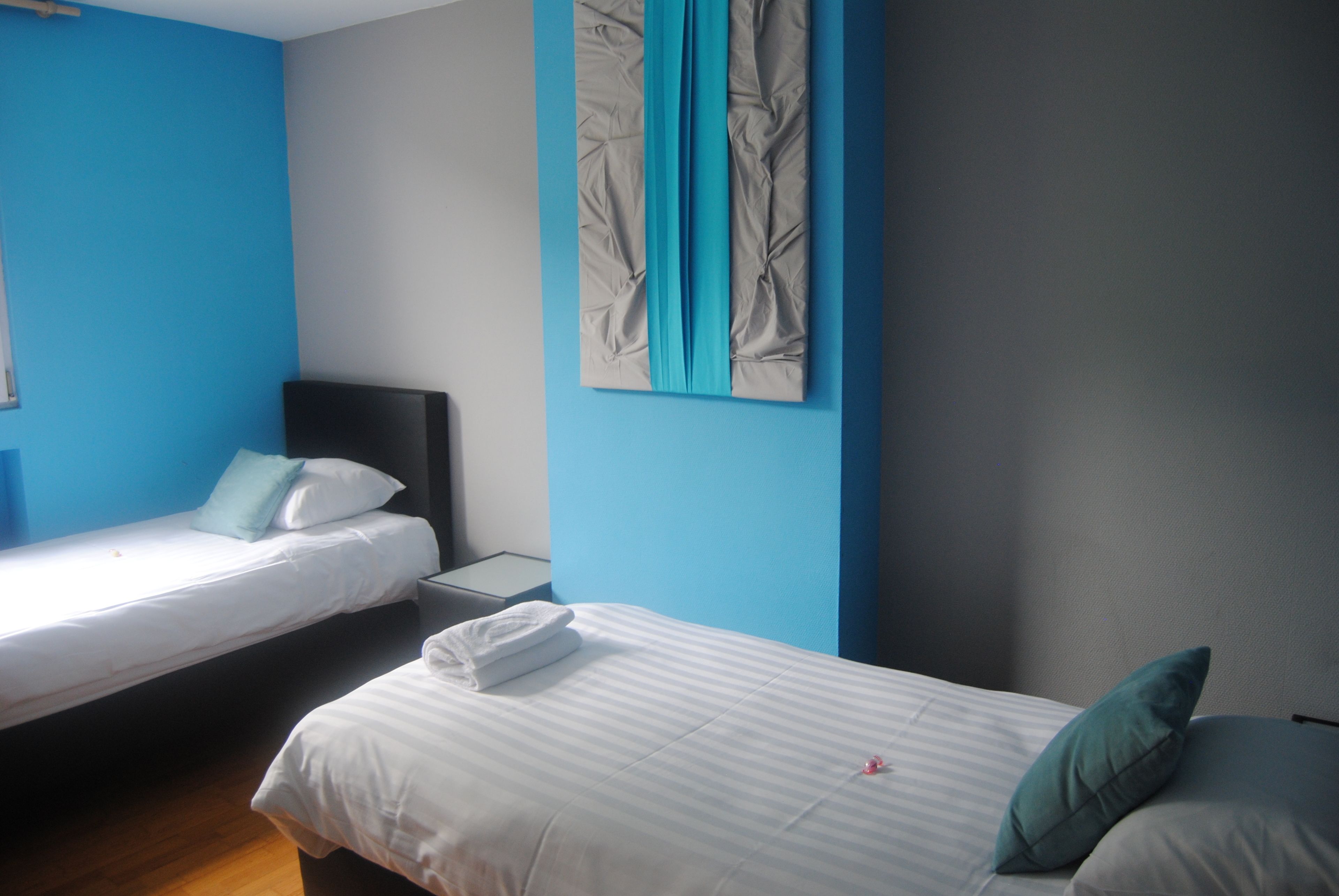 Une chambre avec deux lits simples, une table de chevet et une œuvre d’art accrochée au mur.