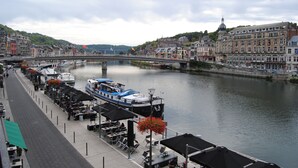 A riverside view with a bridge, boats, and buildings along the water. - L'Inattendu sur la Croisette Dinant Centre (Dinant)