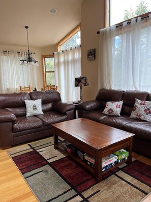 A living room with two brown leather sofas, a wooden coffee table, and a patterned rug.