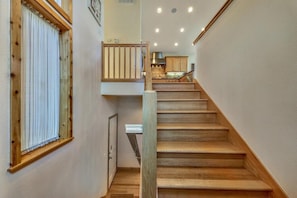 Un escalier en bois mène à un deuxième étage, et on aperçoit un coin cuisine au fond.