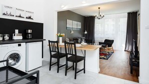A modern kitchen with a washing machine, dining area with chairs, and a small island with a table.
