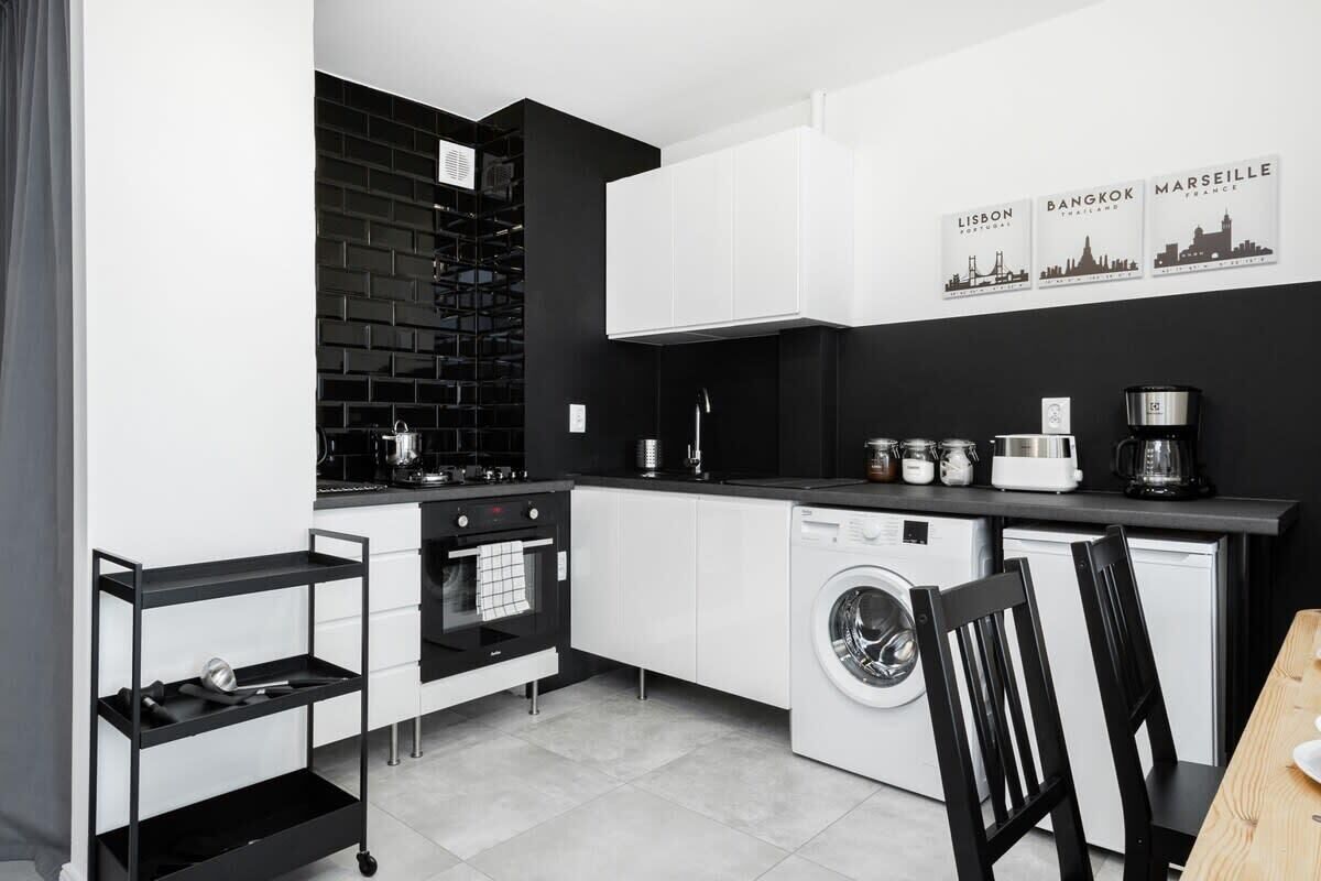 Een moderne keuken met een zwart-wit kleurenschema, voorzien van een vaatwasser, oven en koffiezetapparaat.