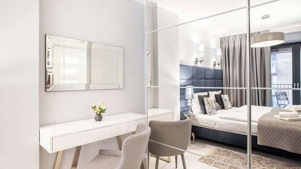A modern bedroom with a large mirror, a desk, and a bed.