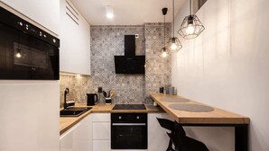 A modern kitchen with a black stove, a microwave, and a black oven. There is a wooden countertop and a black chair.