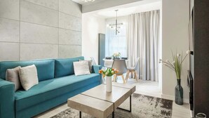 A modern living room with a teal sofa, a coffee table, and a vase of flowers.
