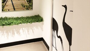 A corridor with a painting of a wooden pier and a wall with a black silhouette of two ostriches. - Hotel du Lac d'Arjuzanx (Morcenx-la-Nouvelle)