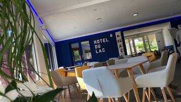 A hotel interior with a blue accent wall, white furniture, and a view of greenery outside.