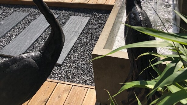 A wooden deck with two large bird sculptures, a small water feature, and a seating area with chairs and tables. - Hotel du Lac d'Arjuzanx (Morcenx-la-Nouvelle)