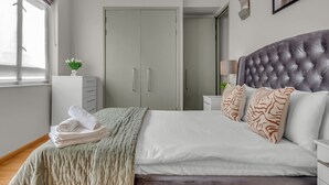 Un dormitorio con cama, armario, mesita de noche y ventana.
