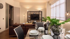 Una sala de estar moderna con comedor, un sofá, un televisor y una planta.