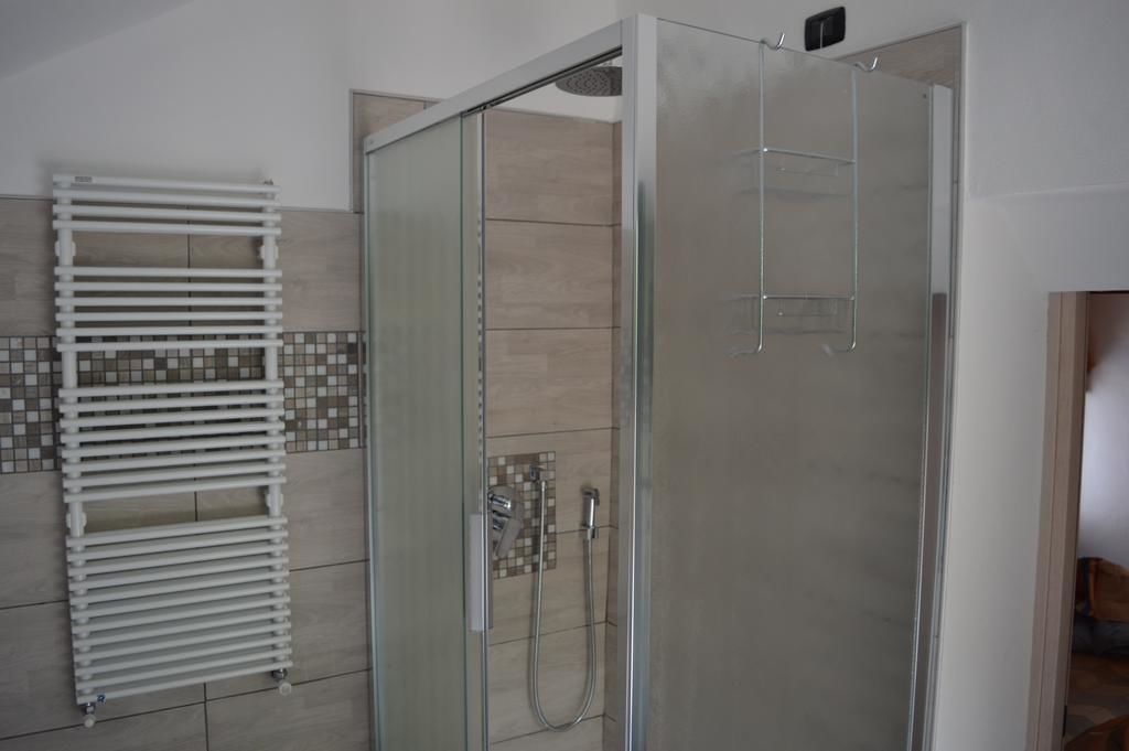 Una doccia con porta in vetro, un termosifone bianco e pareti piastrellate.