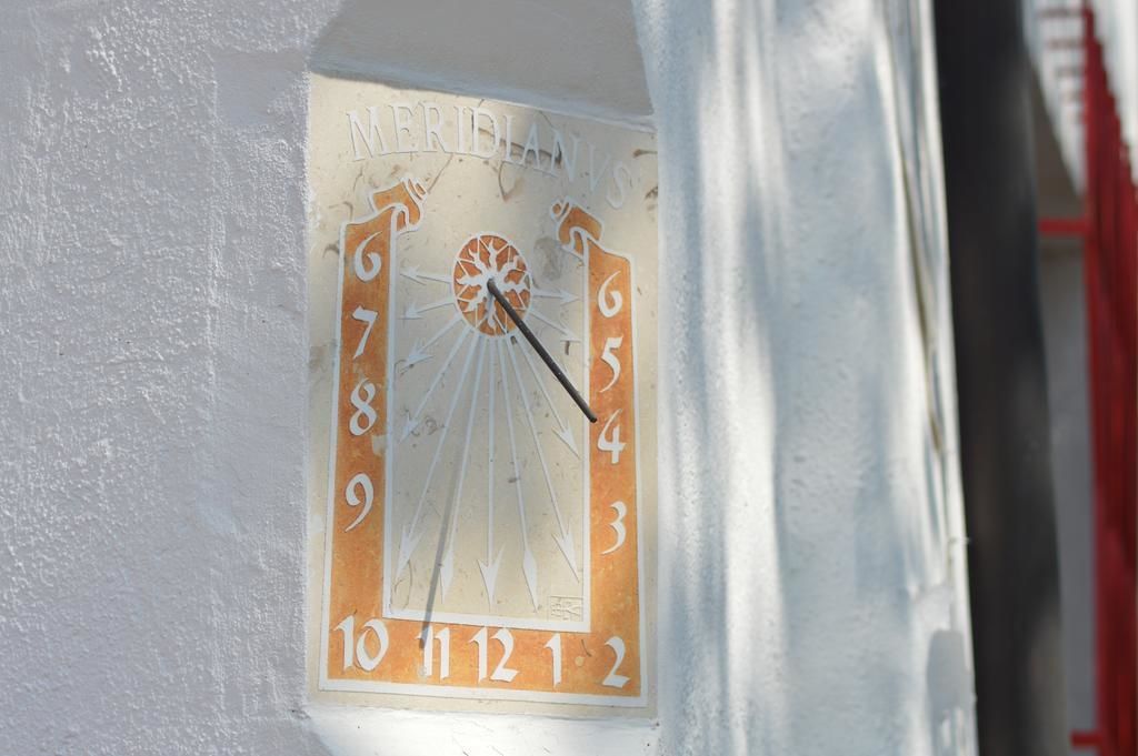 A wall-mounted clock with a sun motif and numbers 1-12.