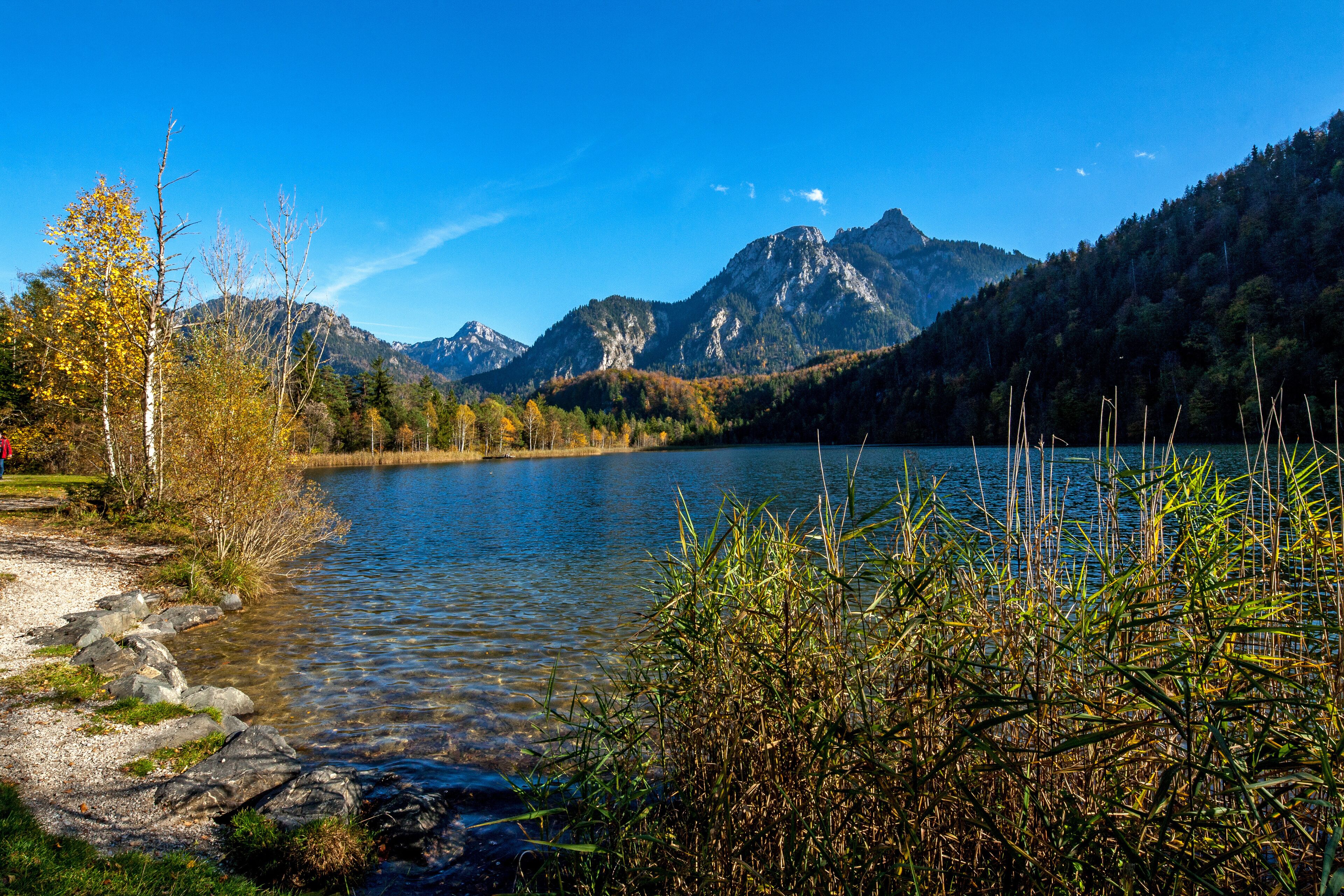 A lake surrounded by mountains, clear water, and autumn foliage.