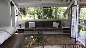 A cozy room with a large window, a built-in bench, a round table, and a wicker ceiling light. - HARBERT PRIVATE LAKEFRONT HOME WITH PRIVATE HOT TUB! (Harbert)