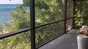 A spacious balcony with large windows overlooking a body of water and dense foliage. - HARBERT PRIVATE LAKEFRONT HOME WITH PRIVATE HOT TUB! (Harbert)
