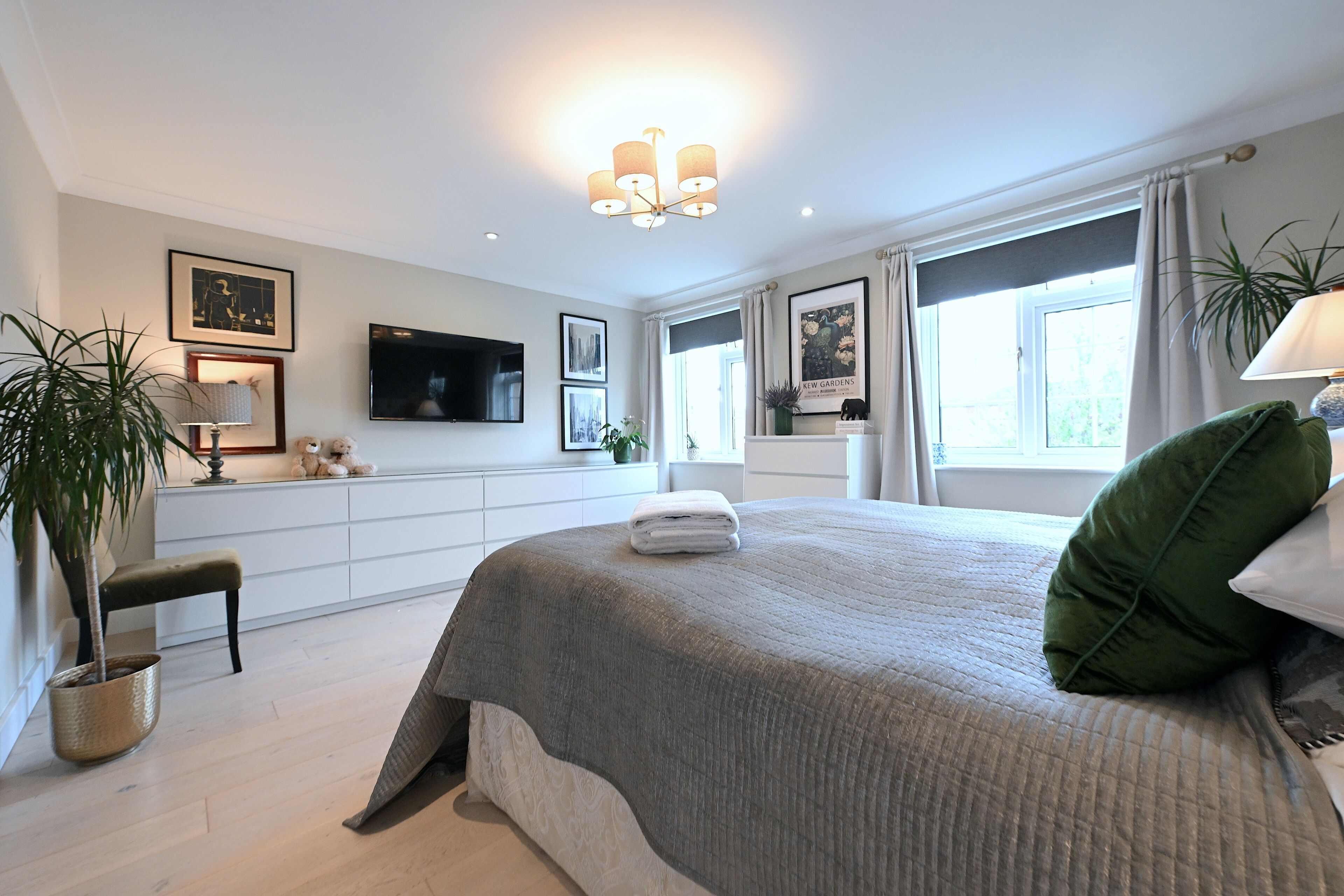 A bedroom with a large bed, a television, a desk, and a window with curtains.