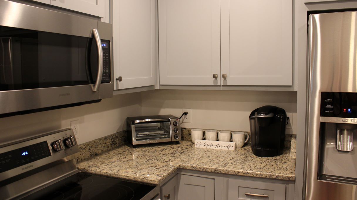 A kitchen with stainless steel appliances, including a microwave, toaster, coffee maker, and refrigerator.