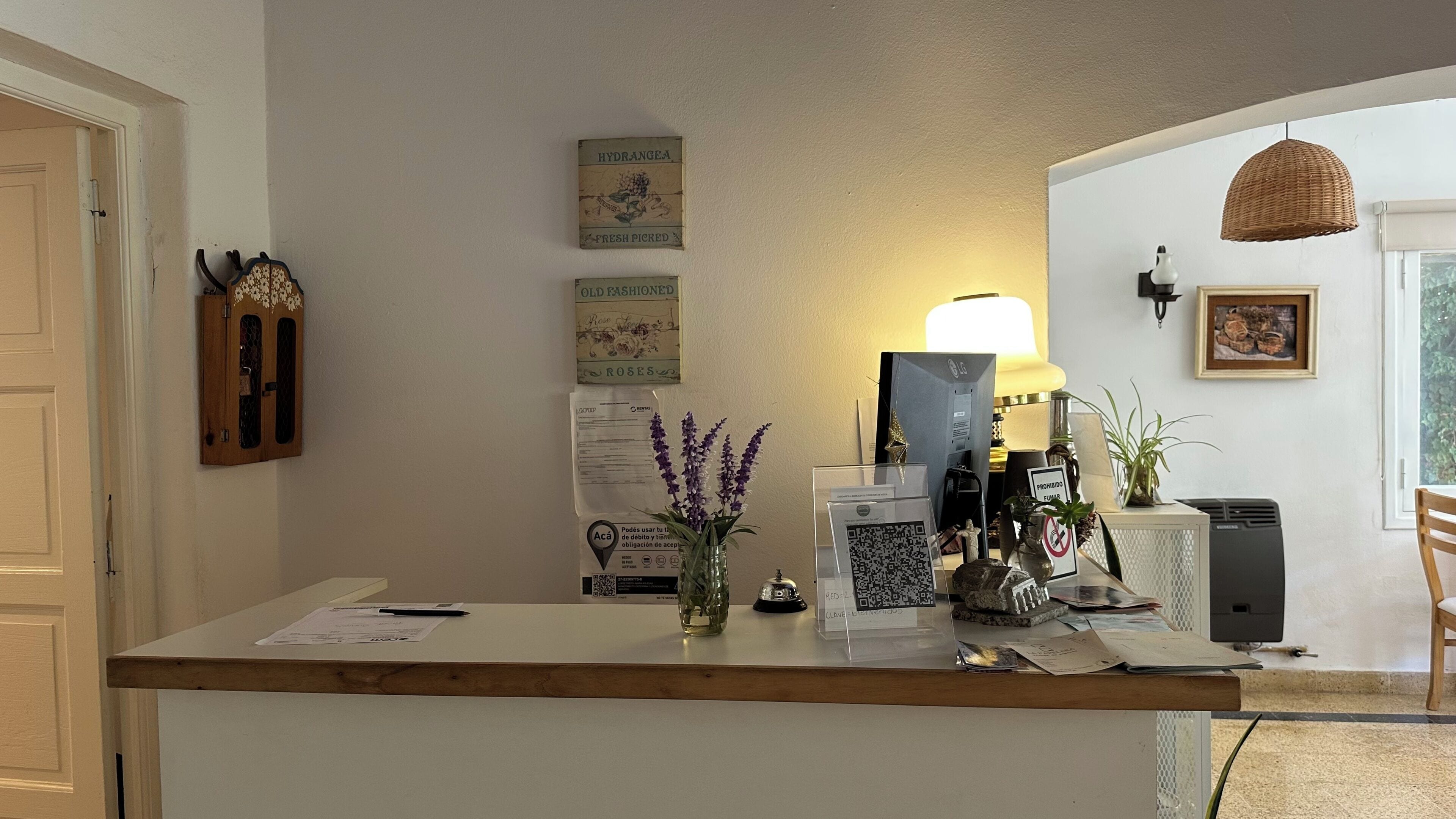 A reception desk with a computer, a lamp, a framed picture, and a QR code sign.