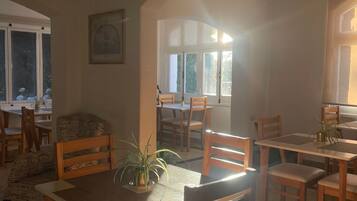 A dining area with wooden tables and chairs, a potted plant, and a framed picture on the wall.