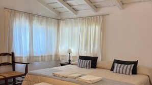 Un dormitorio con una cama grande, una silla, una mesita de noche y un ventilador de techo.