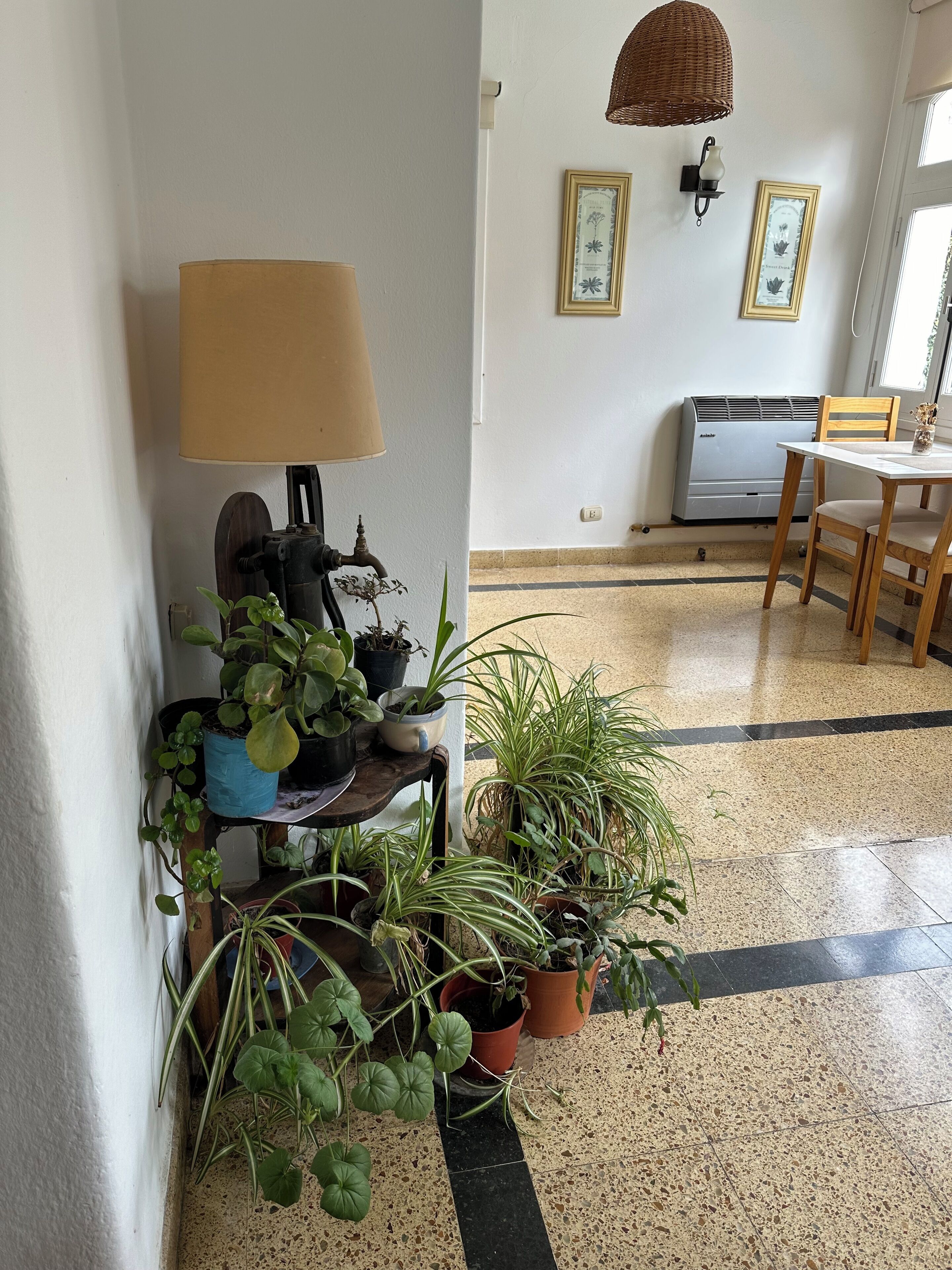 A corner with a lamp, a wall-mounted air conditioner, and a dining table with chairs.
