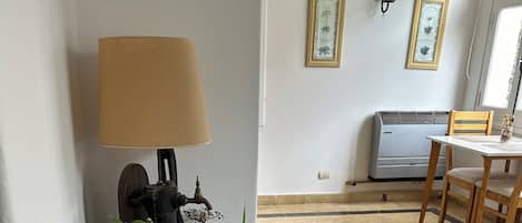 A corner with a lamp, a wall-mounted air conditioner, and a dining table with chairs.