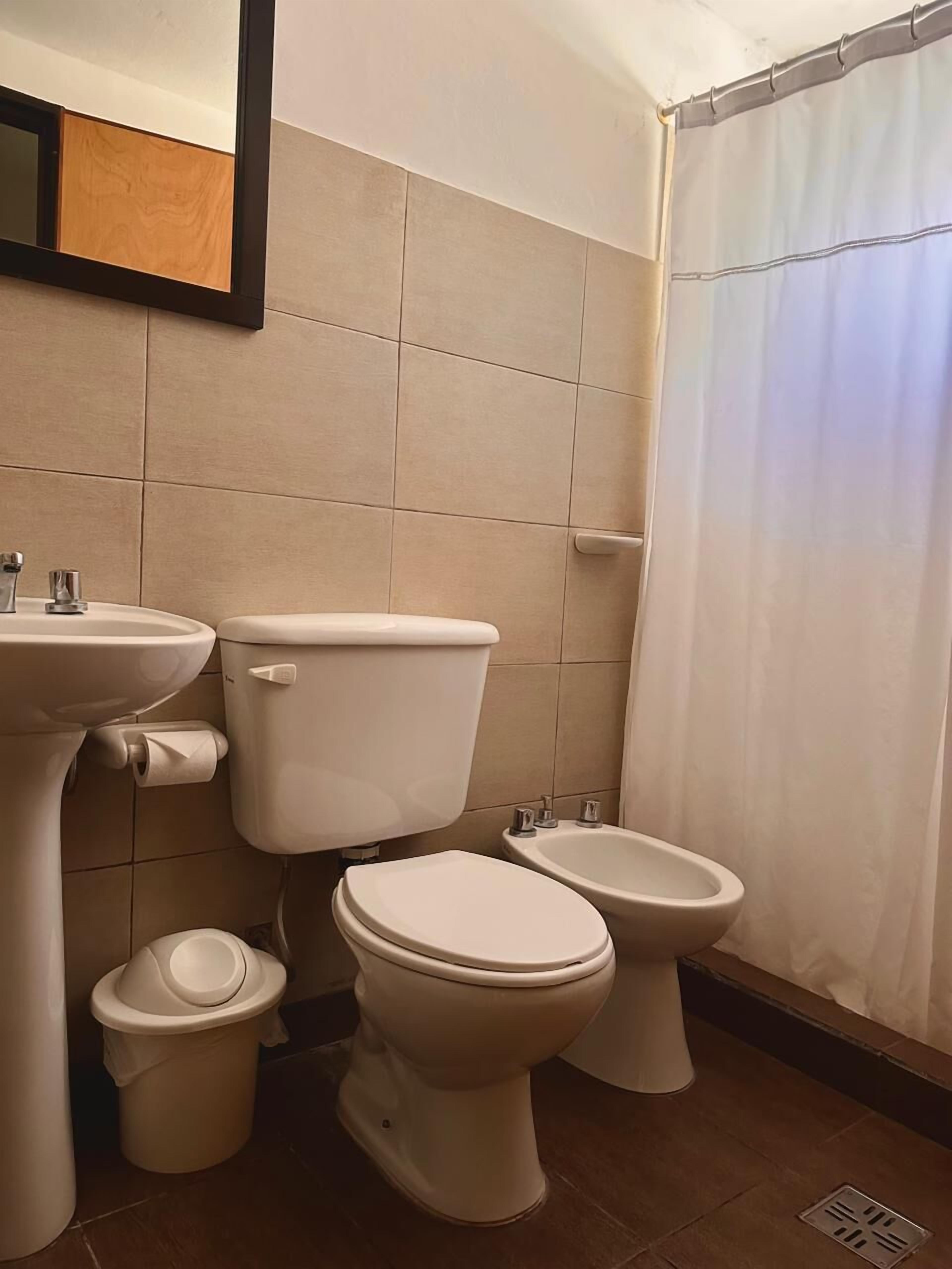 Een badkamer met toilet, toiletbril en wastafel.