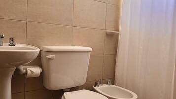 Een badkamer met toilet, toiletbril en wastafel.