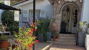 Un patio con plantas en macetas, un sendero de piedra y la entrada de un edificio con un cartel que dice 'BIENVENIDOS'.