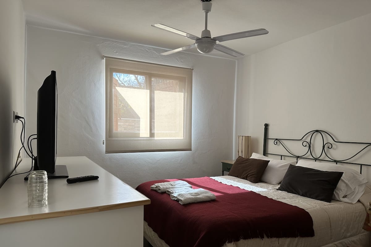 Une chambre à coucher avec un lit, un bureau, un ordinateur et une fenêtre.